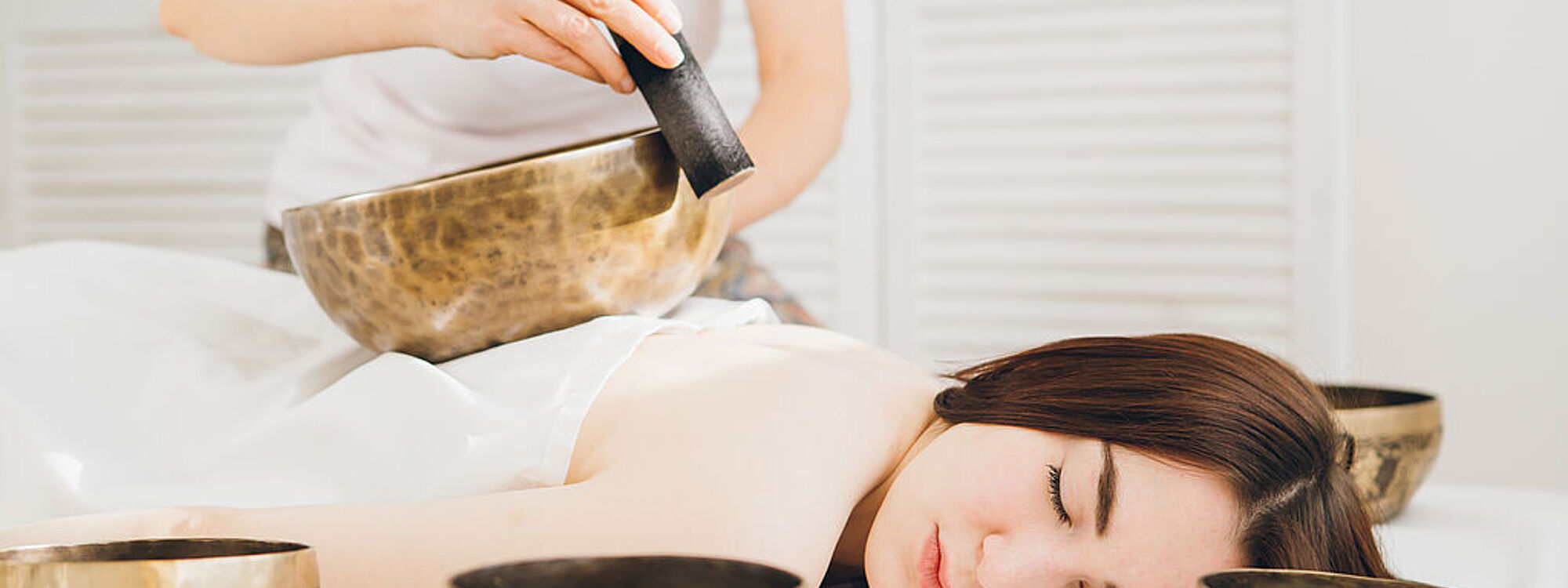 Girl doing massage therapy singing bowls in the Spa